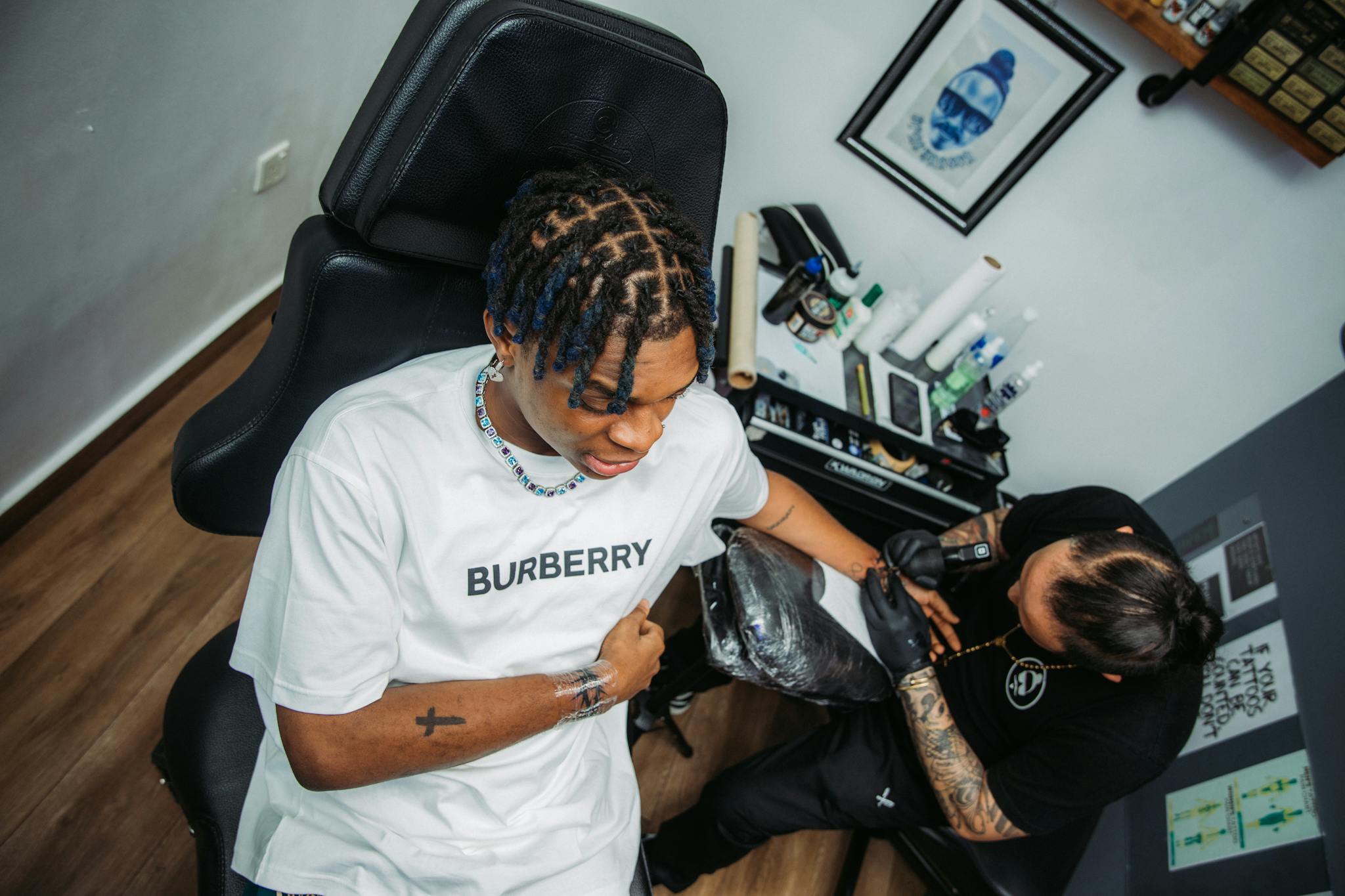 Tattoo artist intricately inking a young client's arm in a modern studio setting.